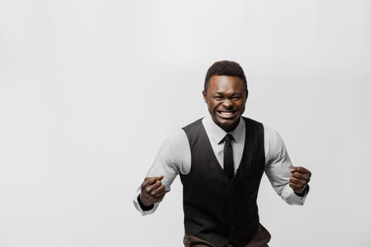 Online bet is won by african man. Man shows his teeth and fists on white background. African won a prize. Online work at home quarantine concept.