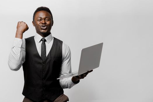Happy black man wins some money in on-line lottery. African lucky man with laptop on white background