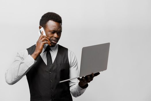 Influential african director speaks by phone and wathes to laptop. Solving business problems at home. On-line work at quarantine period covid 19.