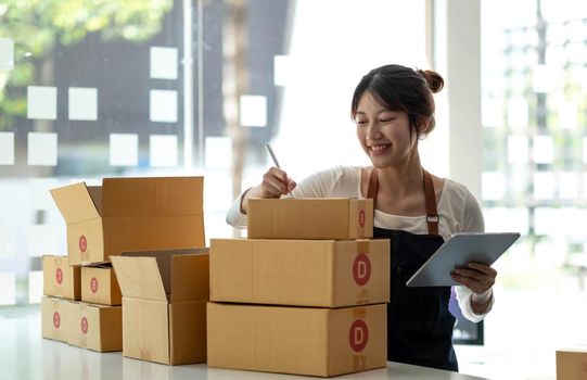 Portrait of Starting small businesses SME owners female entrepreneurs working on receipt box and check online orders to prepare to pack the boxes, sell to customers, sme business ideas online..