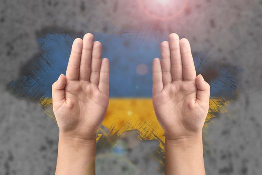 Support for Ukraine and solidarity. Children's hands on the background of the Ukrainian flag. The concept of confrontation and struggle.