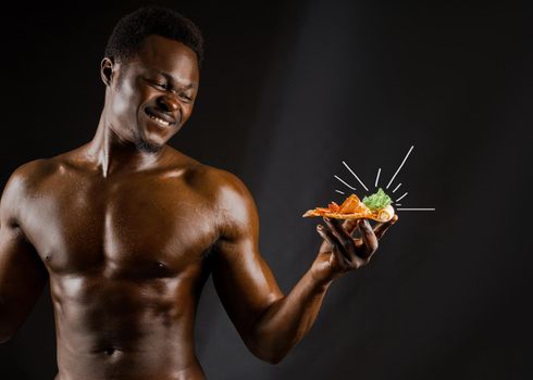 Black handsome naked man eats a pizza with cheese boards. Safety food delivery for people who stays at home. Sexy african man shows 2 pieces of pizza