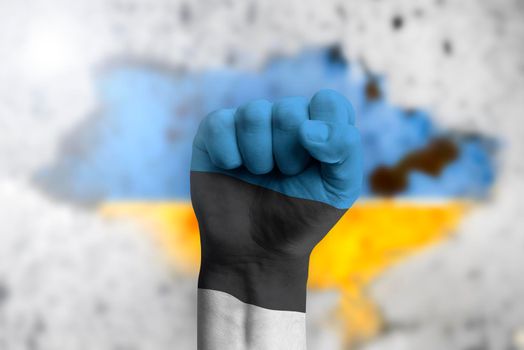 Estonia helps Ukraine and stands in solidarity with it. The concept of humanitarian aid to Ukraine. The fist is painted in the colors of the Estonian flag on the background of the Ukrainian flag.