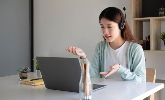 Asian student in casual clothes explaining homework on video conference with teachers on laptop computers at home