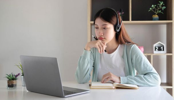 Asian woman student video conference e-learning with teacher on computer in living room at home. E-learning ,online ,education and internet social distancing protect from COVID-19 viruses..