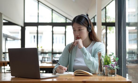 Asian woman student video conference e-learning with teacher on computer in living room at home. E-learning ,online ,education and internet social distancing protect from COVID-19 viruses..