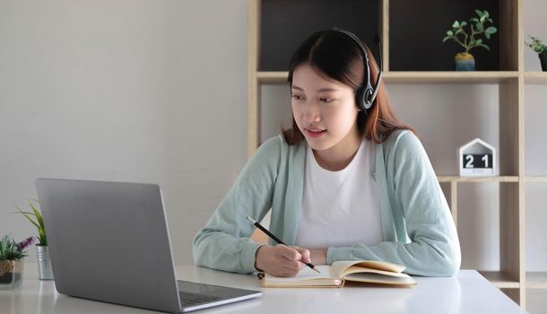 Asian woman student video conference e-learning with teacher on computer in living room at home. E-learning ,online ,education and internet social distancing protect from COVID-19 viruses..