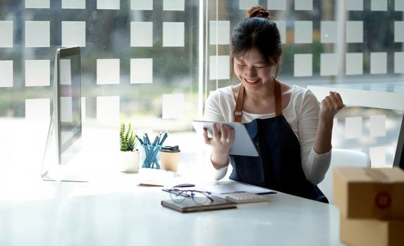 Small business owner wearing an apron is successful selling online using a smartphone parcel box placed at home..