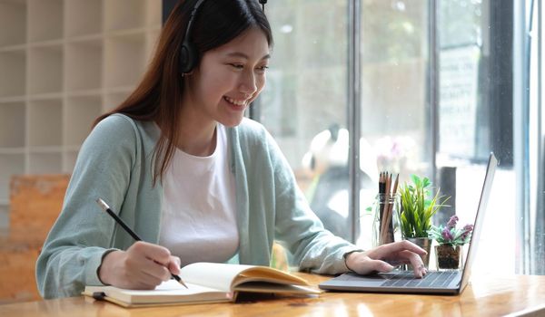 Asian woman student video conference e-learning with teacher on computer in living room at home. E-learning ,online ,education and internet social distancing protect from COVID-19 viruses..