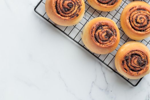 Fresh-baked round buns with poppy seeds on a white table top view