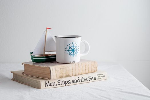 Cup with old books on the white table