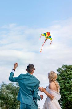 A kite at a wedding. A wedding couple launches a kite into the sky. Bride and groom fly a kite together on their wedding day