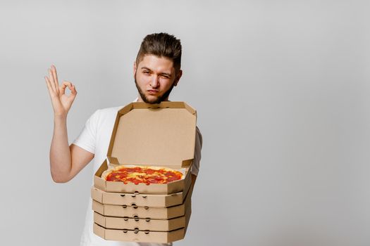 Young caucasian man shows that OK. On-line pizza delivery from restaurant. Safety delivery without coronavirus. pizza advertise for pizzeria