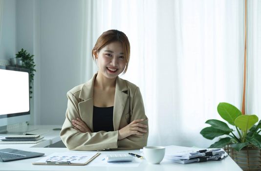 Portrait of confident young entrepreneur sitting at modern workplace and smiling to camera..