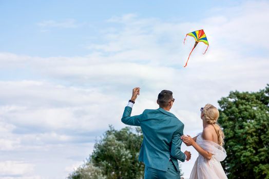 A kite at a wedding. A wedding couple launches a kite into the sky. Bride and groom fly a kite together on their wedding day