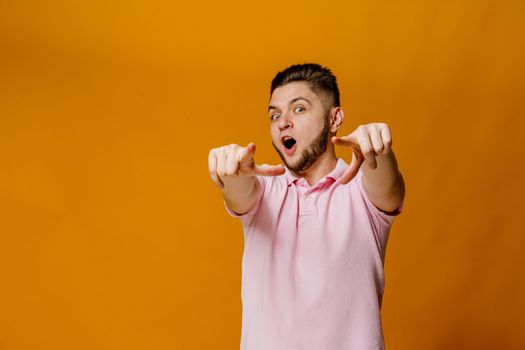 Handsome bearded caucasian man points to you. Confident man wears casual style and stands over orange backround. On-line business for students.