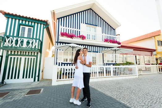 Young couple in white clothes walks around street in Aveiro, Portugal near colourful and peaceful houses. Lifestyle. Tourism trip in Portugal