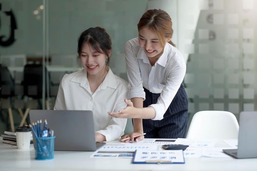 Two Young Asian businesswoman discuss with new startup project Idea presentation, analyze planning and financial statistics and investment market at office..