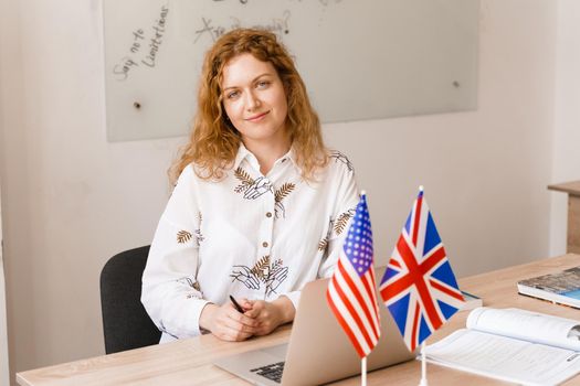 Close-up portrait of a beautiful smiling student on bright background. Happy ginger female teacher smiling to her colleagues