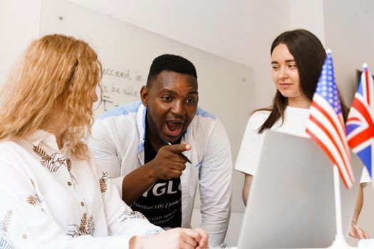 Online multiethnic attractive group of teachers study and laught, discuss something. Remote work in multinational group with laptop.