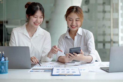 Two Young Asian businesswoman discuss with new startup project Idea presentation, analyze planning and financial statistics and investment market at office..