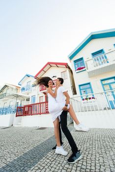Young couple stays in tango pose and looks each others in Aveiro, Portugal near colourful and peaceful houses. Lifestyle. Having fun