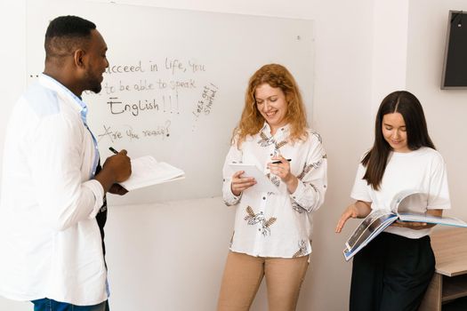 Multiethnic students and teacher study foreign languages together in class. Studing with laptop. Black handsome student study with white people together.