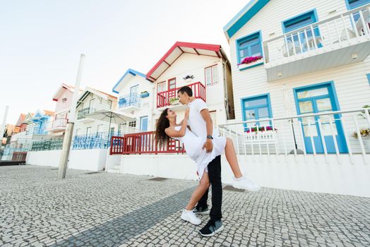 Young couple stays in tango pose and looks each others in Aveiro, Portugal near colourful and peaceful houses. Lifestyle. Having fun, laughs, smiles.