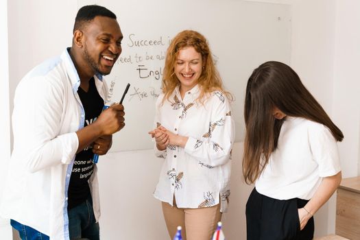 Multiethnic students and teacher study foreign languages together in class. Studing with laptop. Black handsome student study with white people together.