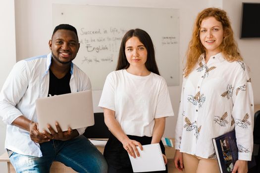 Multiethnic students and teacher study foreign languages together in class. Studing with laptop. Black handsome student study with white people together