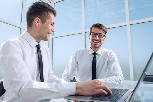 Two businessmen are sitting in the office and discussing the conclusion of a new deal