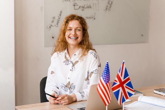 Close-up portrait of a beautiful smiling student on bright background. Happy ginger female teacher smiling to her colleagues