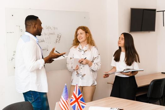 Multiethnic students and teacher study foreign languages together in class. Studing with laptop. Black handsome student study with white people together.