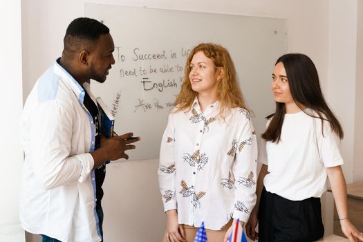 Multiethnic students and teacher study foreign languages together in class. Studing with laptop. Black handsome student study with white people together.