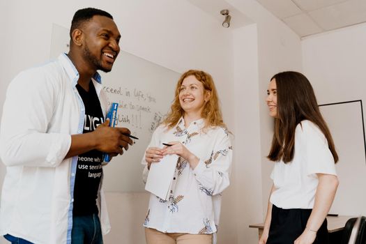 Multiethnic happy students and black teacher study foreign languages and smile and laught together in class. Studing with laptop.