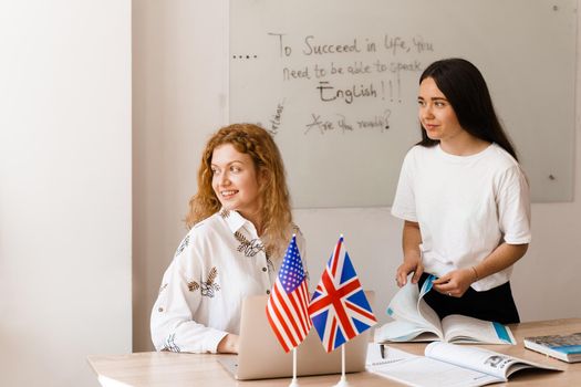 Teacher of english asks student in white class. 2 girls student answers to teacher. Working in group. Study english and british language.