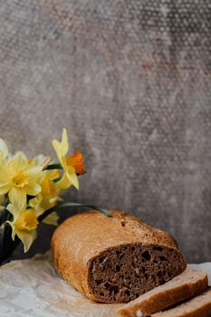 Rustic grain bread with oats, flax seeds, sunflower seeds and sesame seeds on a wooden board with a jute sack and a rolling pin on the background.