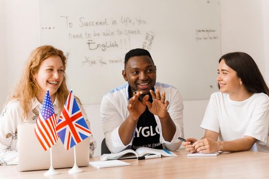 Online multiethnic attractive group of teachers study and laught, discuss something. Remote work in multinational group with laptop.