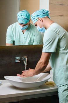 Doctors looks at the cleanliness of his hands after washing under a stream of water. Wash your hands under running water.