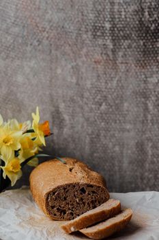 Fresh loaves of bread with wheat and gluten on a wooden table.