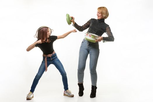 Mom and daughter have fun using kitchen utensils, the girl attacks, mom defends herself with a pot lid