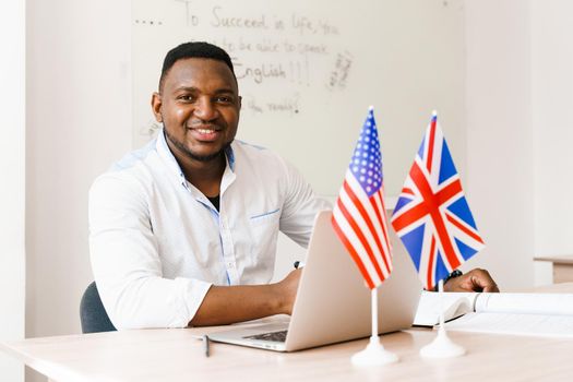 Black handsome man uses his laptop for online work according social distancing. Speaking by web camera with colleagues. Scientist works at home
