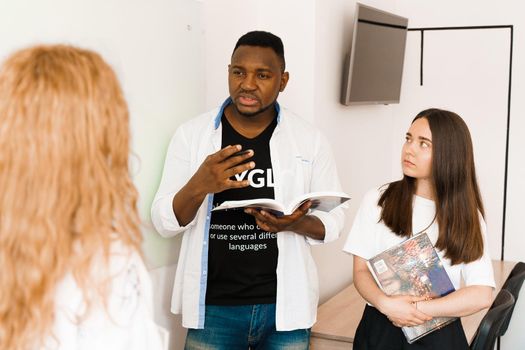 Attractive friendly-looking colleagues are working together in an office, discussing something on white background