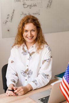 Close-up portrait of a beautiful smiling student on bright background. Happy ginger female teacher smiling to her colleagues