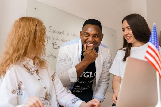 Online multiethnic attractive group of teachers study and laught, discuss something. Remote work in multinational group with laptop.