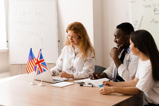 Online multiethnic attractive group of teachers study and laught, discuss something. Remote work in multinational group with laptop.