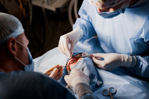 Blepharoplasty plastic surgery operation for modifying the eye region of the face in medical clinic. Surgeon sutures the eyelid