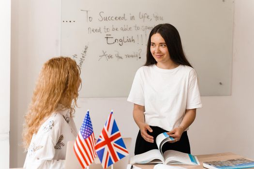 Teacher of english asks student in white class. 2 girls student answers to teacher. Working in group. Study english and british language.