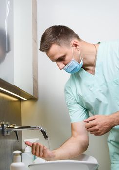 Professional surgeon washes his hands in clinic before surgery operation. Procedure to stop coronavirus