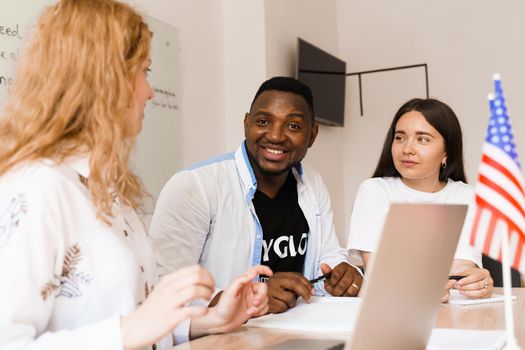 Online multiethnic attractive group of teachers study and laught, discuss something. Remote work in multinational group with laptop.